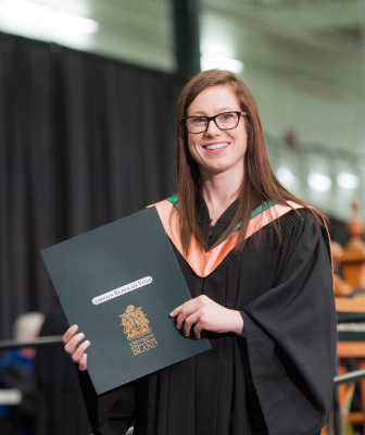 A graduate stands with her degree
