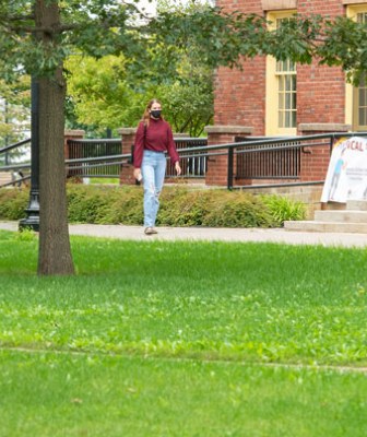 a student walks across campus in front of SDU main building